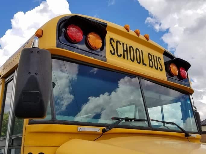 front view of yellow school bus rental with cloud reflection in windshield